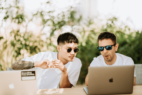 two people talking laptops macbooks social media manager